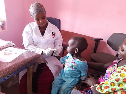 A KCCR employee takes blood from the fingertip of a small child to test for malaria.